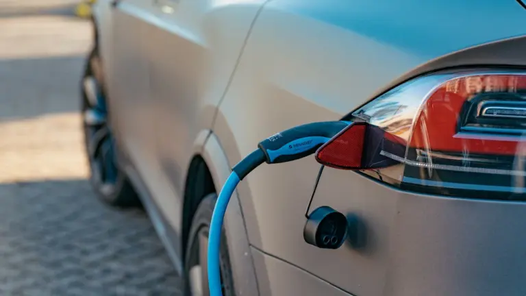 Elektromobilio įkrovimo procesas su prijungtu laidu moderniame automobilyje dienos metu.