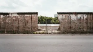 Istorinės Berlyno sienos fragmentai su metaline tvora, primenantys padalytos Europos praeitį.