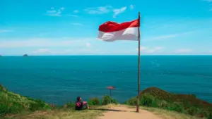 Indonezijos vėliava plevėsuoja pajūryje, simbolizuojanti šalies laisvę ir nepriklausomybės kelią.