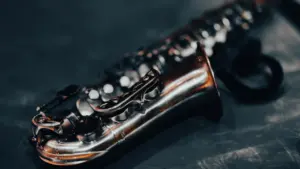 Iš arti nufotografuotas sidabrinis saksofonas tamsiame fone, skirtas romantiškam muzikiniam renginiui.