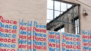 Sienos piešinys su užrašu World Peace šalia tuščio atviro pastato lango.